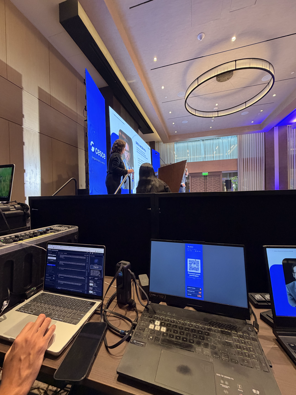 Mesa de control de Iarvix durante el evento: la consola del operador y la pantalla lateral mostrando el código QR de acceso con los contadores en vivo