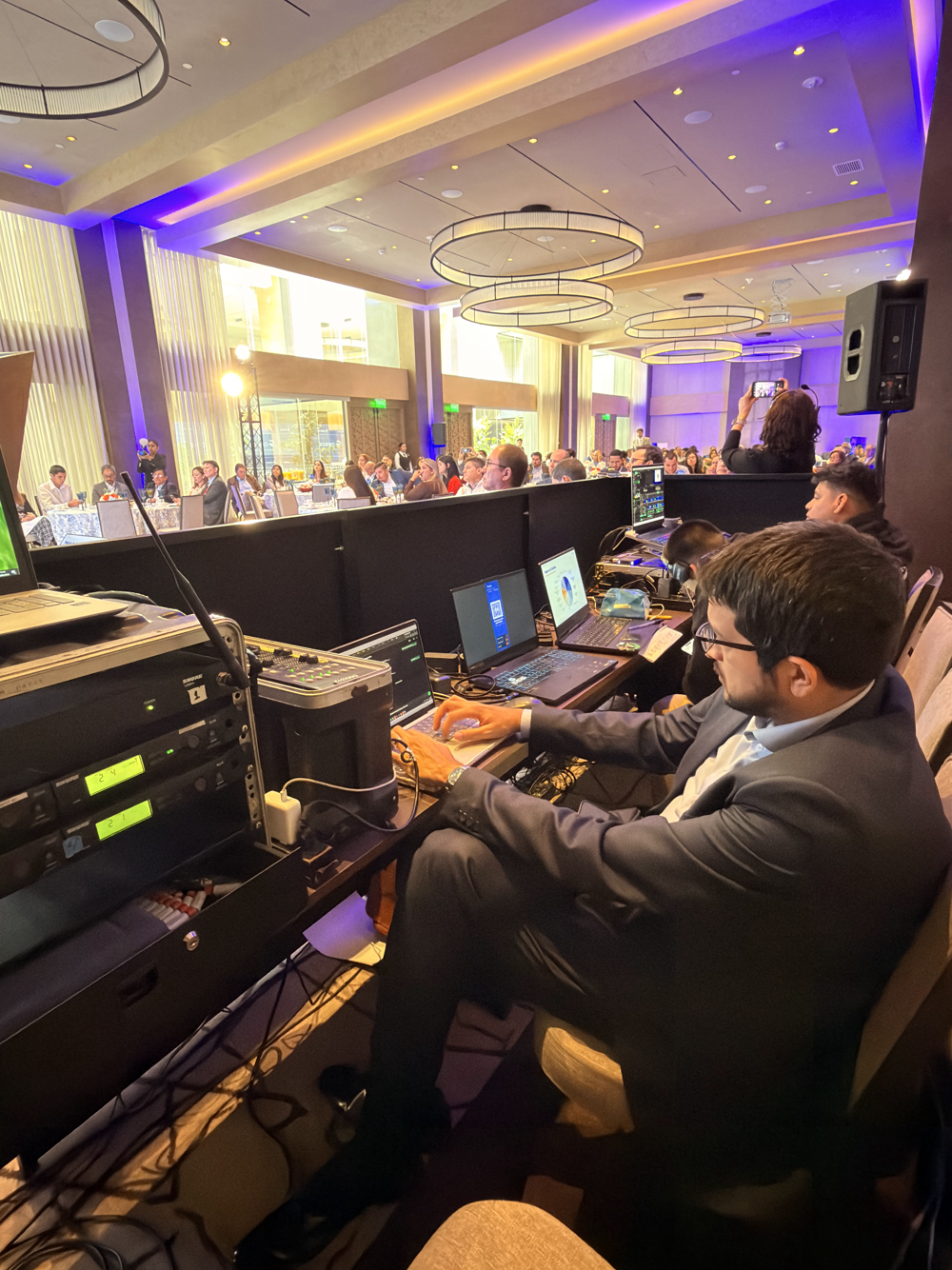 El operador de Iarvix conduciendo la plataforma de inteligencia artificial desde la mesa de control, con el salón completo al fondo